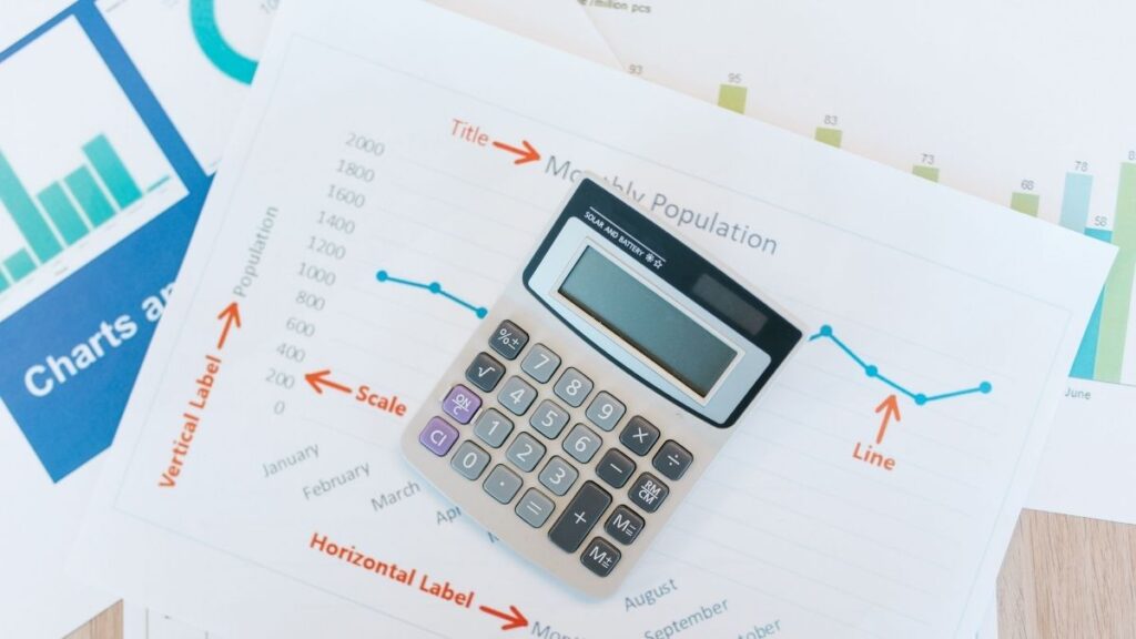 Calculator placed on financial charts and monthly reporting documents